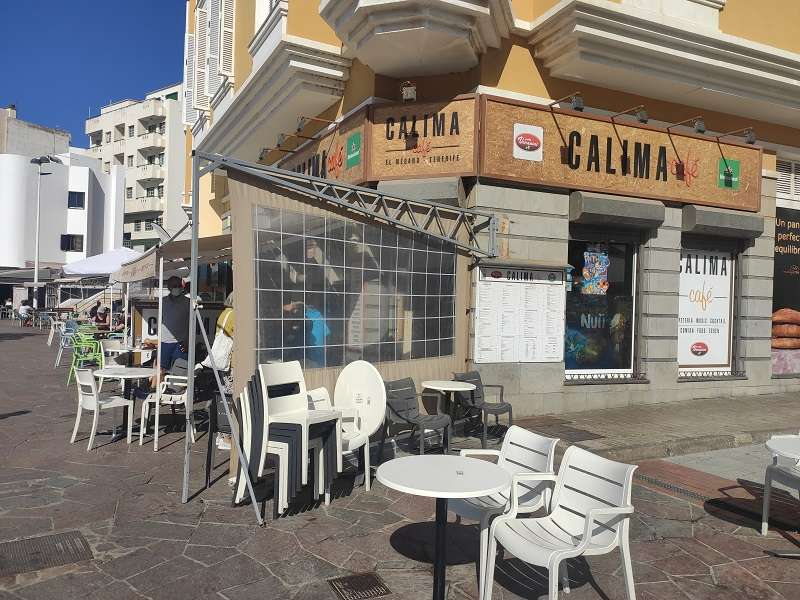 Exterior del Calima Cafe con mesas y sillas en la plaza de El Médano